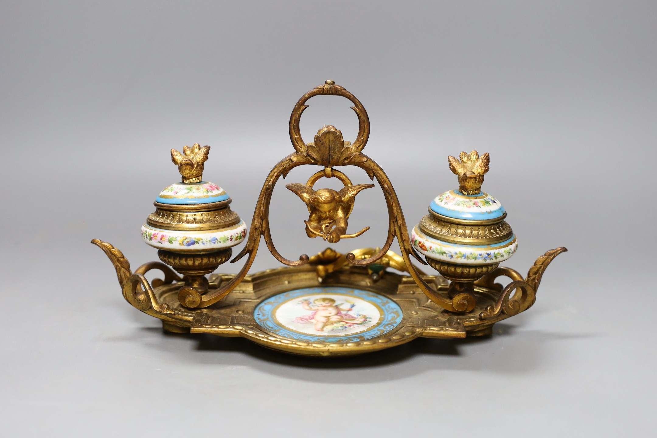 A late 19th century ormolu and 'Sevres' inkstand with cherub and floral decoration - 29cm long